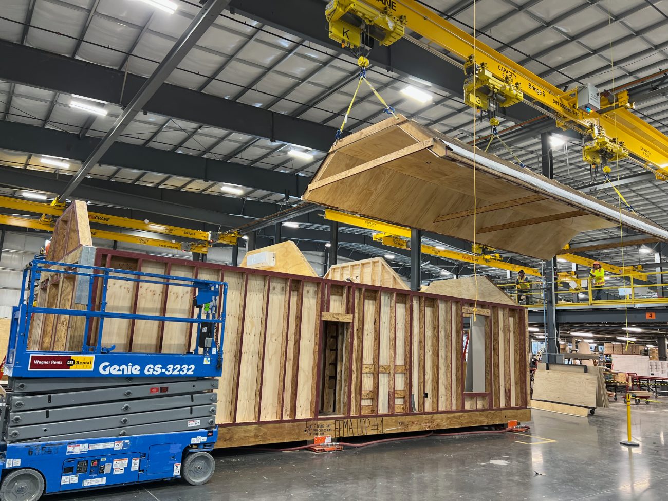 A roof cassette being craned onto a framed housing module on the factory floor
